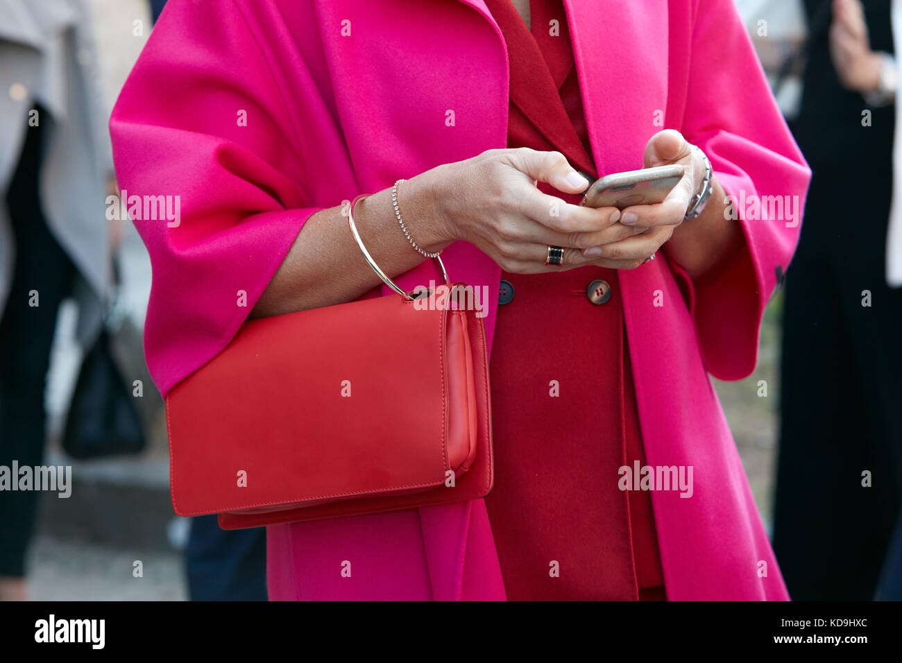 Mailand - 21. September: Frau suchen auf Smartphone mit rotem Leder Tasche und Fuchsia Coat vor Luisa beccaria fashion show, Mailand fashion week St Stockfoto