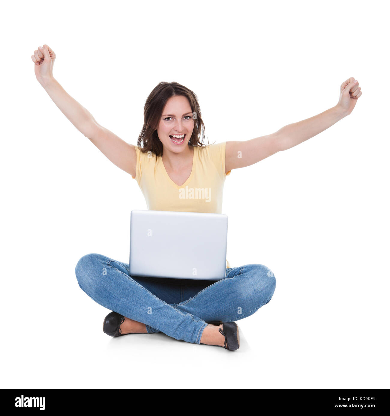Erregte junge Frau mit Laptop sitzen auf weißem Hintergrund Stockfoto