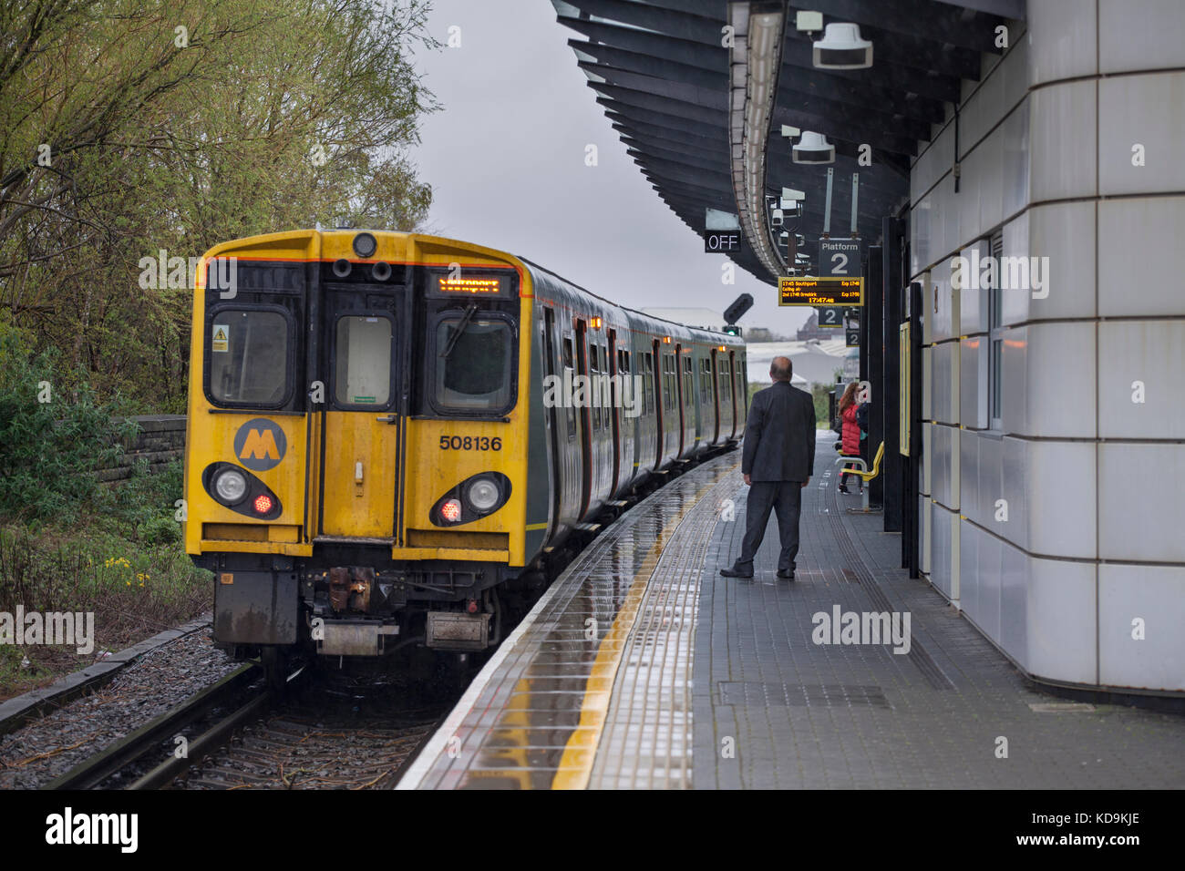 Der Dirigent der 1721 Hunts Cross - Southport Merseyrail zug Kontrolle der Türen vor der Abreise aus Sandhills Bahnhof, Liverpool Stockfoto