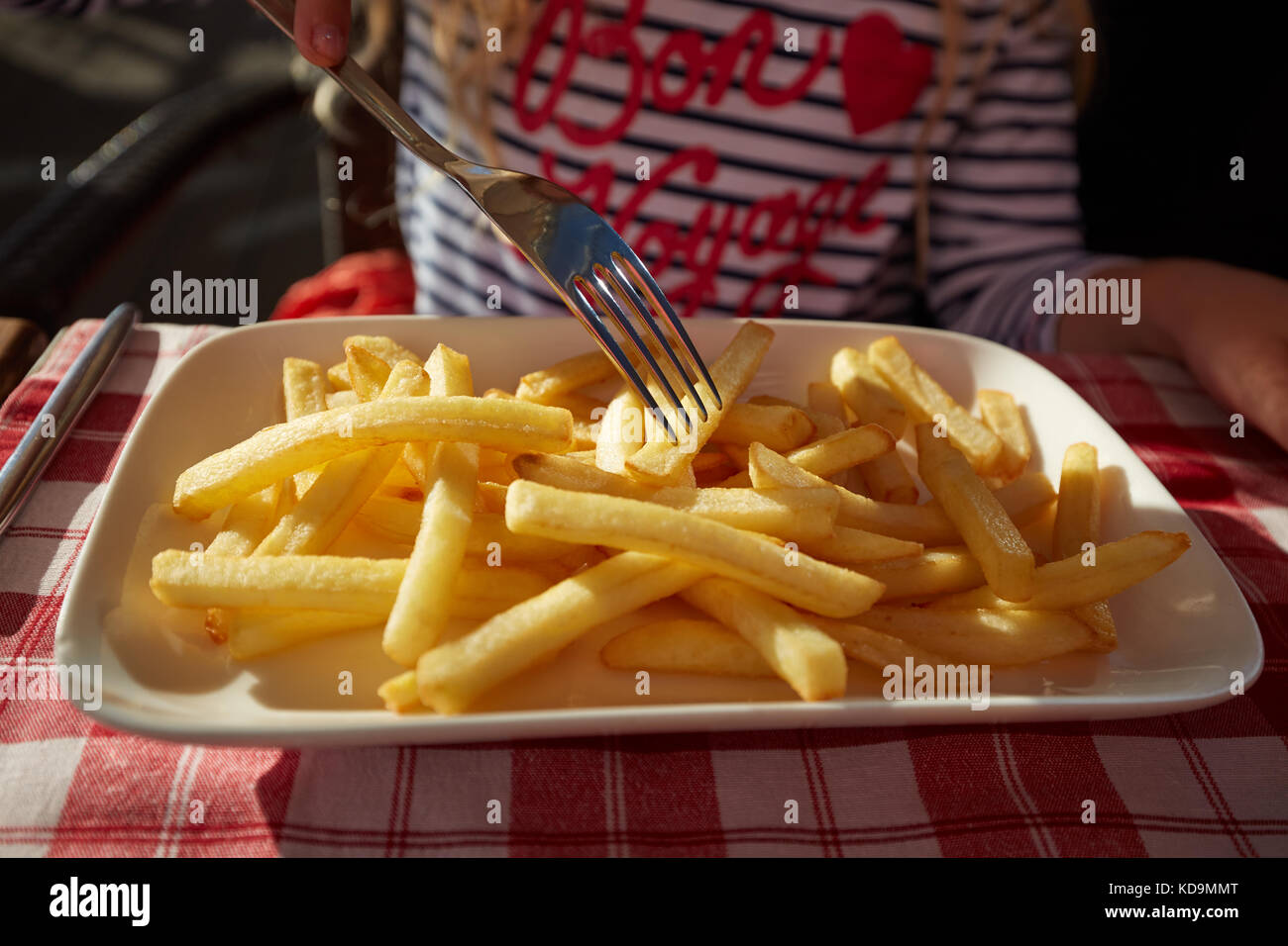 Nahaufnahme foto Vorschule Mädchen isst Pommes frites Kartoffeln sitzen im Cafe im Freien. Stockfoto