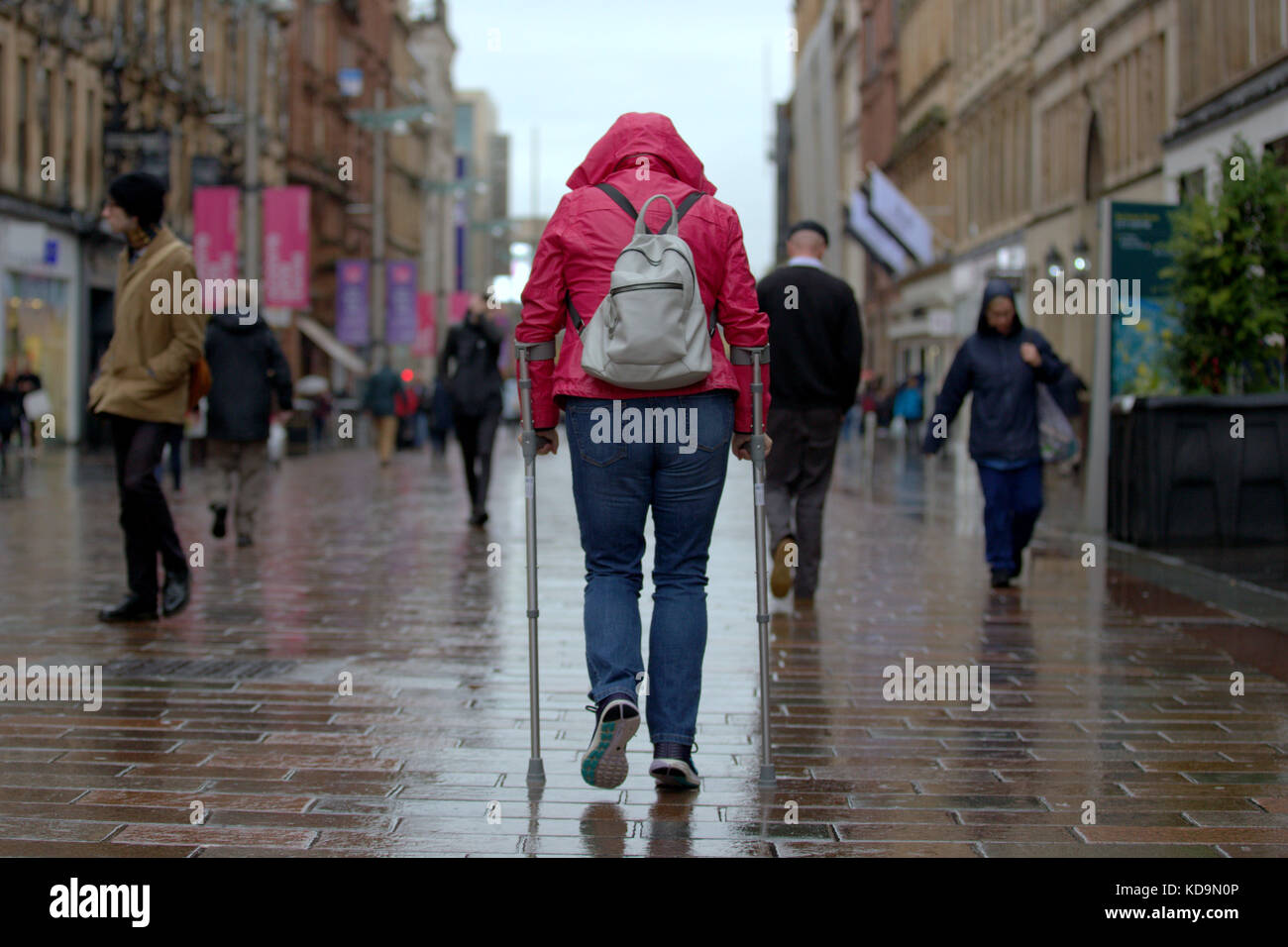Mädchen mit Stöcken auf die Buchanan Street Glasgow in der Perspektive von hinter Krücken Gehhilfen Stockfoto