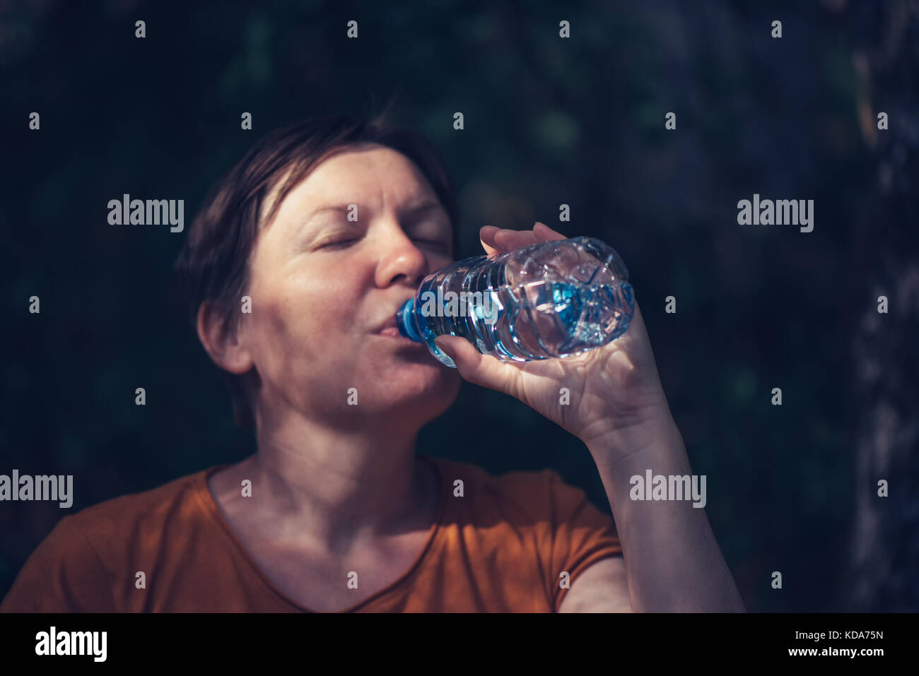 Frau trinkt Wasser draußen. durstig nach kaukasisch Weiblich erfrischend nach einem langen Spaziergang durch den Park auf sonnigen Sommertag, selektiver Fokus Stockfoto