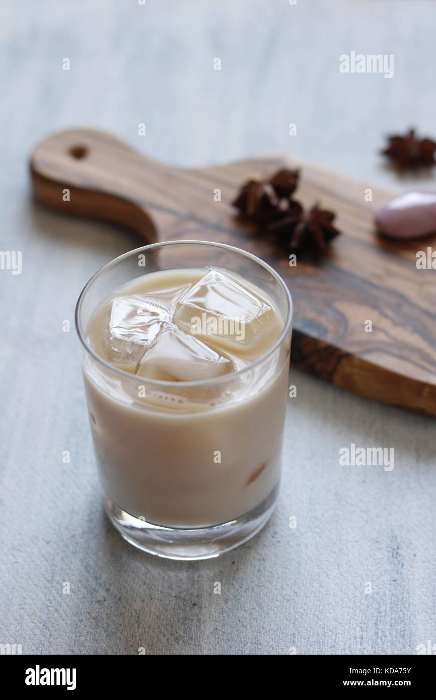 Thailändischer süßer Tee mit Sternanis und kondensierter Milch auf Glas mit Eiswürfeln gewürzt. Schneidebrett und Sternenanisen auf dem Hintergrund Stockfoto