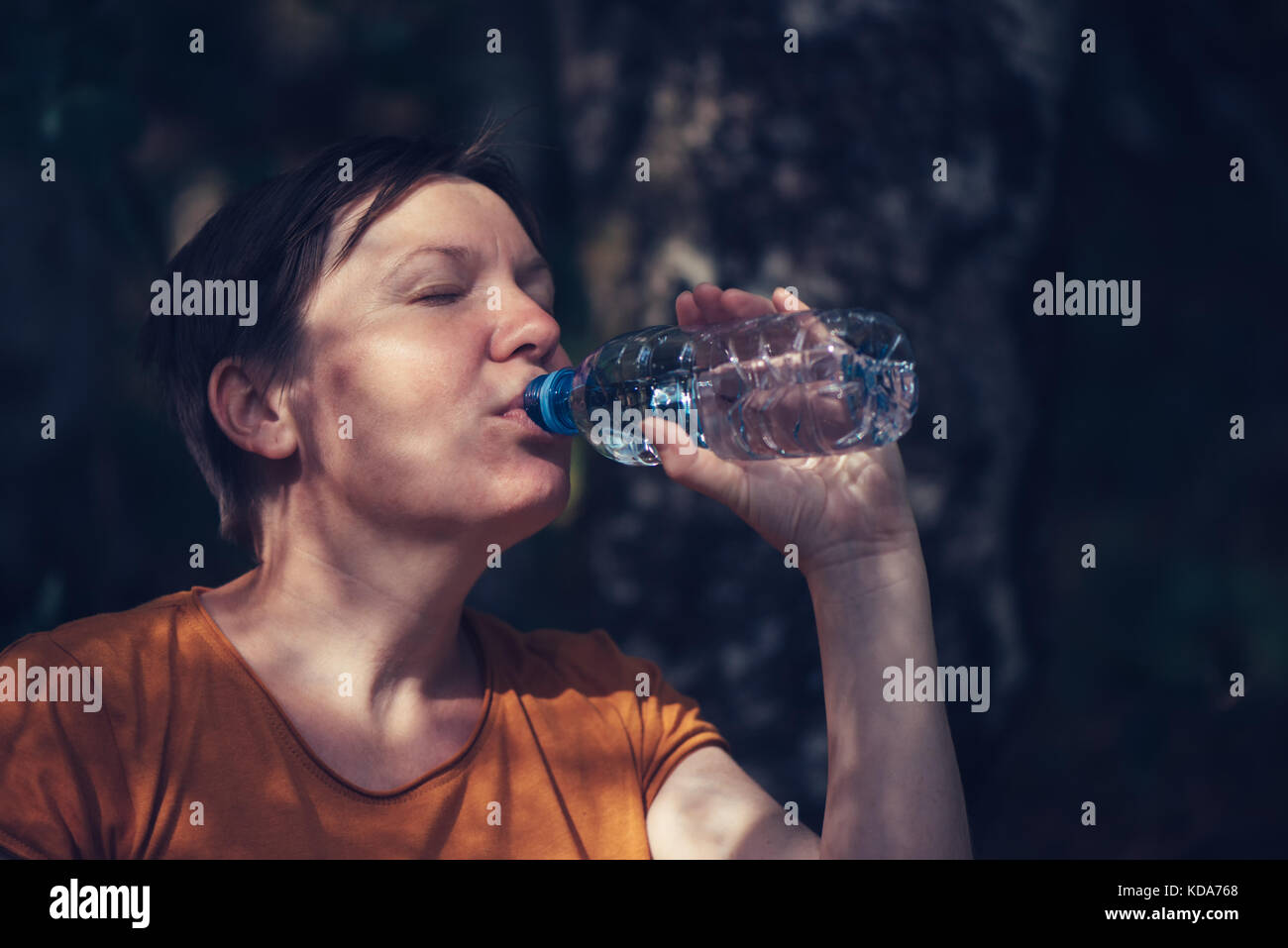 Frau trinkt Wasser draußen. durstig nach kaukasisch Weiblich erfrischend nach einem langen Spaziergang durch den Park auf sonnigen Sommertag, selektiver Fokus Stockfoto