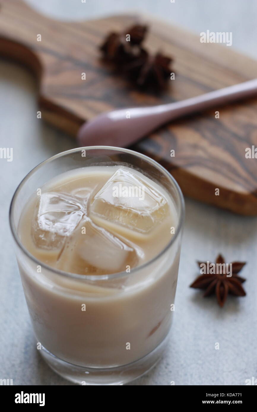 Thailändischer süßer Tee mit Sternanis und kondensierter Milch auf Glas mit Eiswürfeln gewürzt. Schneidebrett und Sternenanisen auf dem Hintergrund Stockfoto