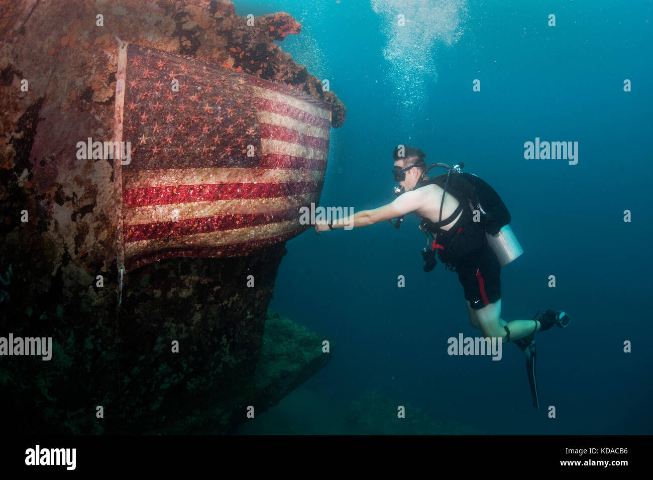 Ein U.S. Navy sailor behebt die amerikanische Flagge auf den amerikanischen Tanker bei einem Tauchgang in der Nähe der Militärbasis guam Juni 21 Hung, 2017 in Apra Harbor, Guam. Die amerikanischen Tanker ist eine versunkene konkrete Lastkahn, der während des Zweiten Weltkrieges zu transportieren war Stockfoto