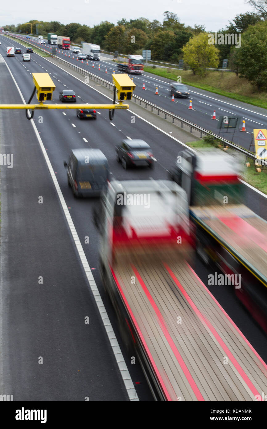 Leuchtend gelbe Blitzer in einer durchschnittlichen Geschwindigkeit prüfen mit Verkehr fließt durch eine Baustellen Bereich auf einem britischen Autobahn oder Schnellstraße. Stockfoto