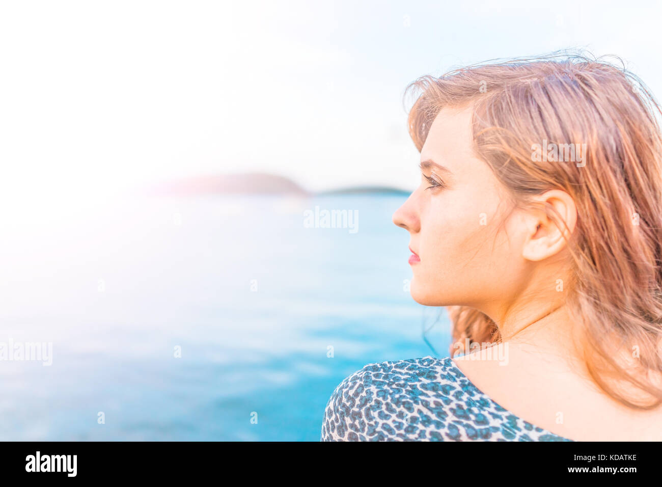 Profil Portrait von Jungen glücklich lächelnde Frau am Rande von Dock in Bar Harbor, Maine sitzen bei Sonnenuntergang mit goldenes Sonnenlicht und tan zu Seite Stockfoto