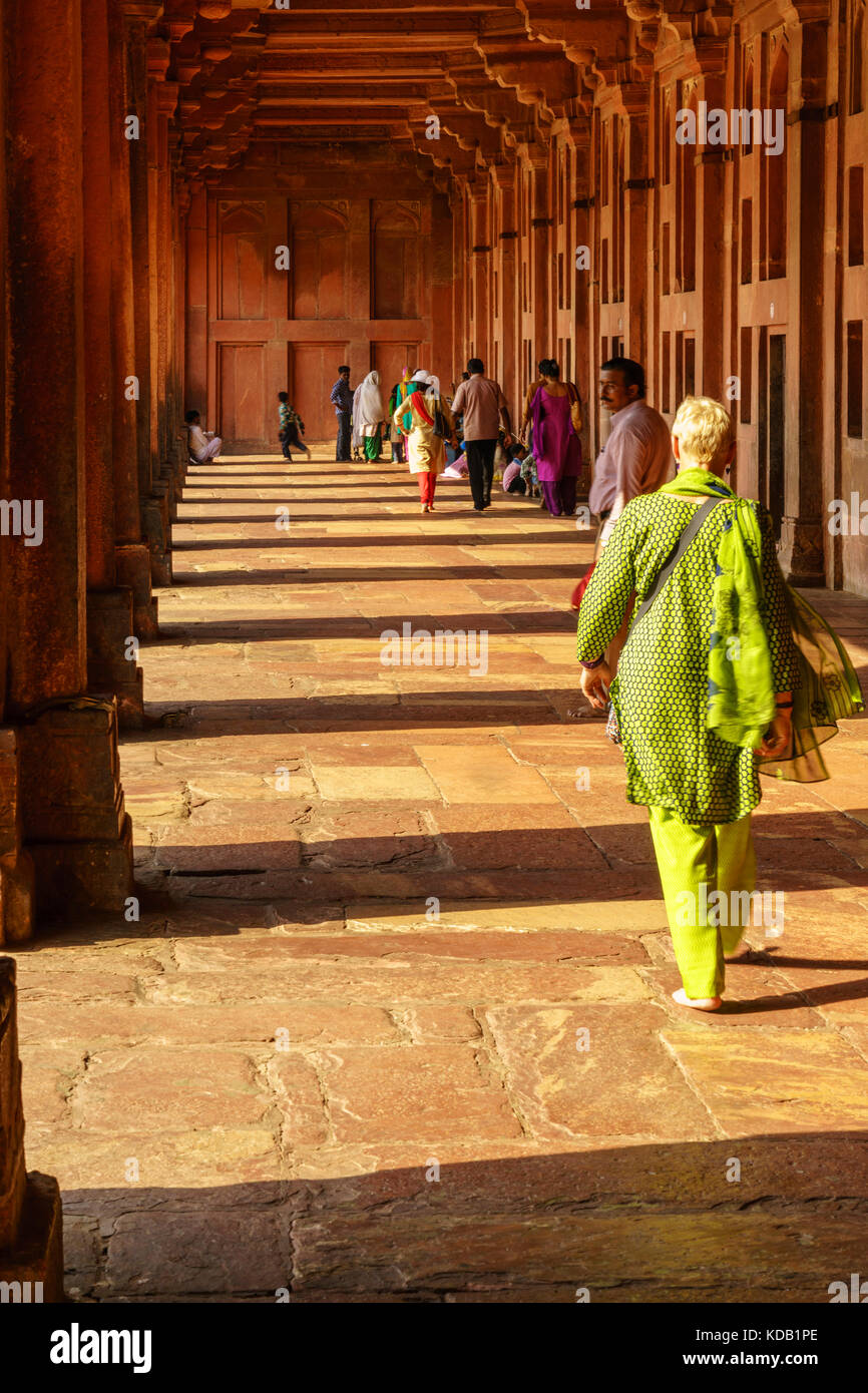 Eine westliche Frau in der indischen Kleidung spazieren durch einen Korridor an einem Tempel in Fatehpur Sikri bei Agra, Indien angezogen Stockfoto
