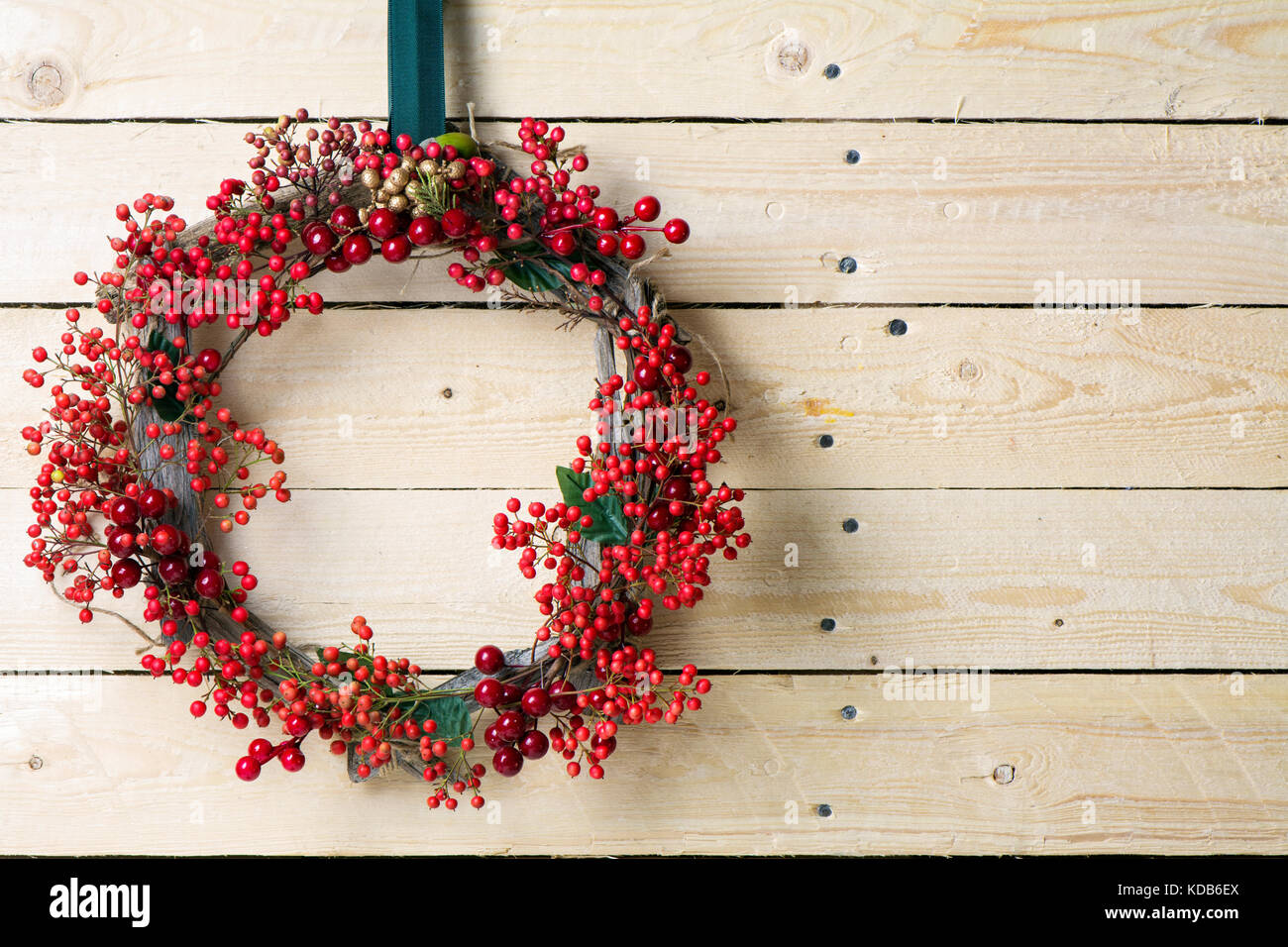 Weihnachten Kranz von Evergreen und Beeren auf hölzernen Hintergrund. Natürliche nandian Netzwerk und rustikalem Holz Krone Stockfoto