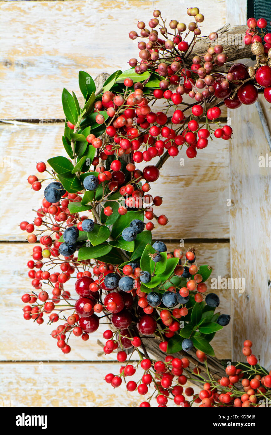 Weihnachten Kranz detail von Evergreen und Beeren auf hölzernen Hintergrund. Natürliche nandian Netzwerk, grüner Zweig und rustikalem Holz Krone Stockfoto