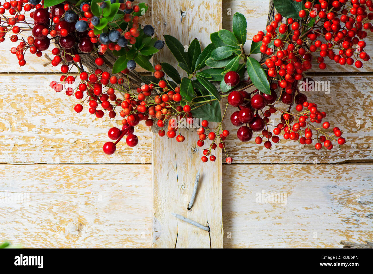 Weihnachten Kranz detail von Evergreen und Beeren auf hölzernen Hintergrund. Natürliche nandian Netzwerk, grüner Zweig und rustikalem Holz Krone Stockfoto