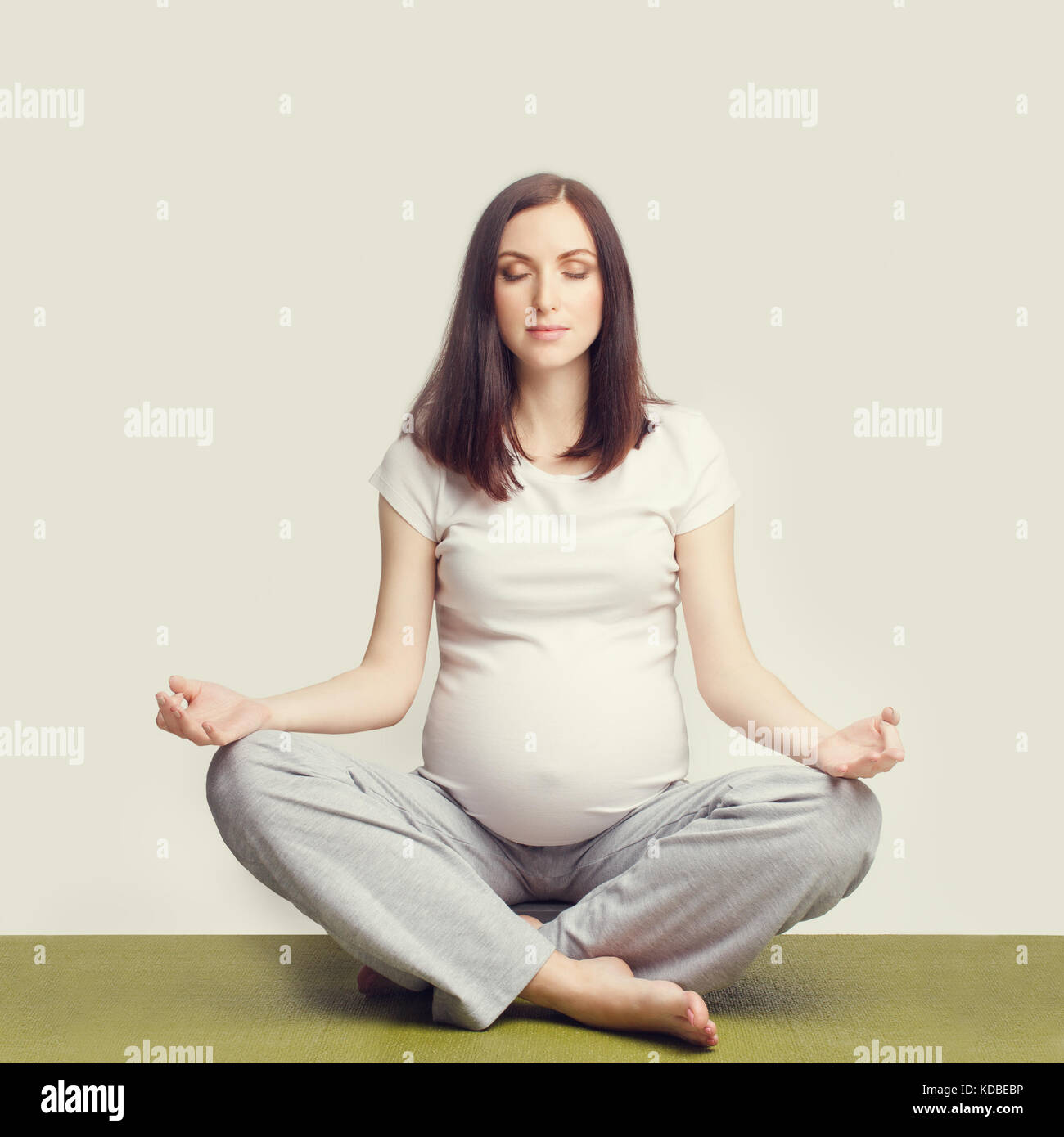 Schwangere Frau sitzt im Lotussitz Stockfoto