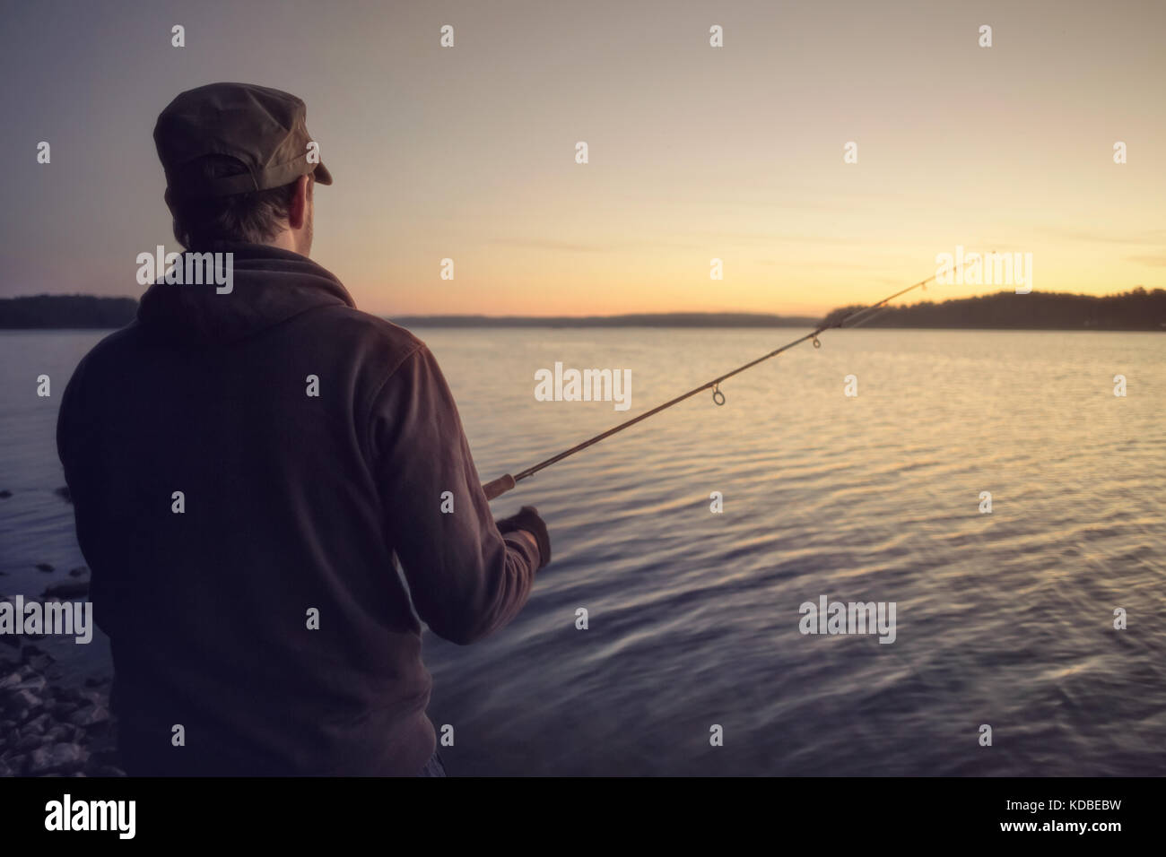 Mann, der an einem See angeln nach Sonnenuntergang Stockfoto