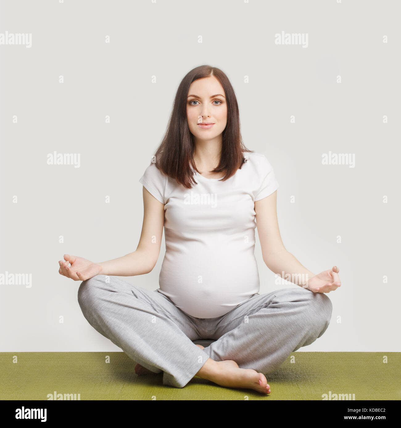 Schwangere Frau sitzt im Lotussitz Stockfoto