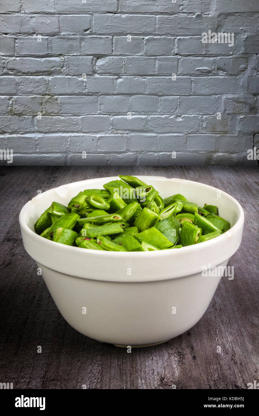 Gehackte runner Bohnen in eine Porzellanschüssel an einem hölzernen Tisch Stockfoto