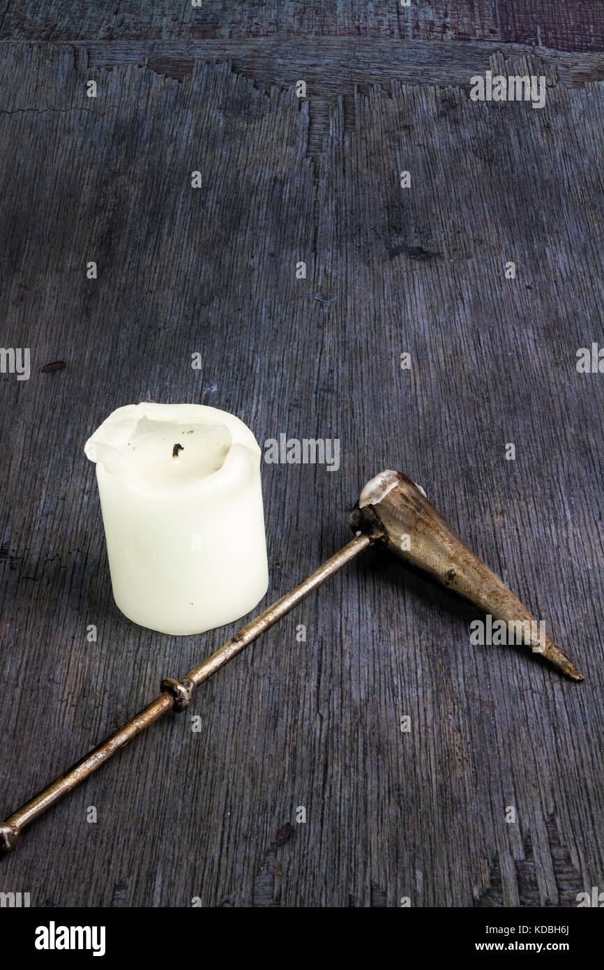 Weiße Kirche Kerze mit einem Metall Kerzenlöscher auf einer hölzernen Hintergrund Stockfoto