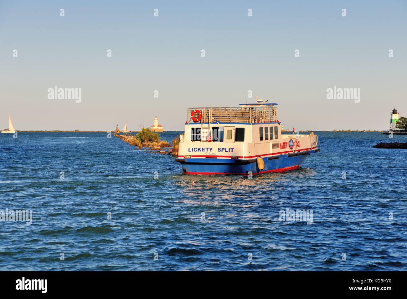 Ein Wassertaxi wird von der untergehenden Sonne hervorgehoben, wie es Segel vom Navy Pier Chicago in Chicago Hafen. Chicago, Illinois, USA. Stockfoto