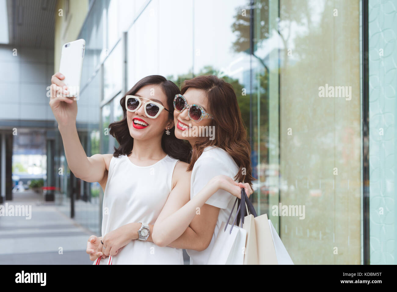 Die besten Freunde der Frauen unter selfie in lustige Gesichter holding Käufer tragen und trendige Mode Kleidung Stockfoto