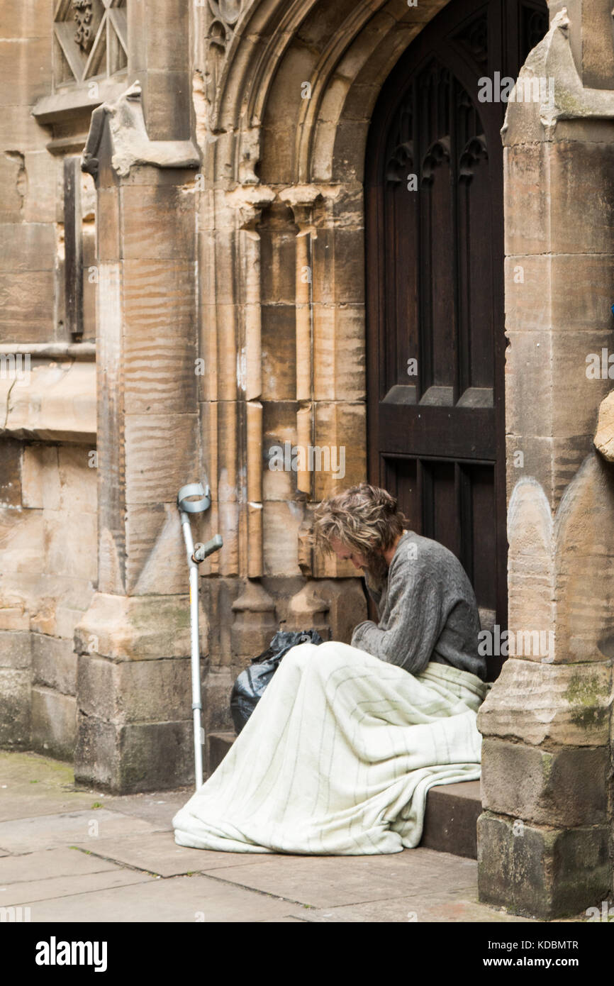 Obdachloser in York Großbritannien ruht. Decke über seine Knie, Arm Krücke, lehnte sich gegen die Wand. Der Mann lokking sehr traurig, verloren und einsam. graues Haar Stockfoto