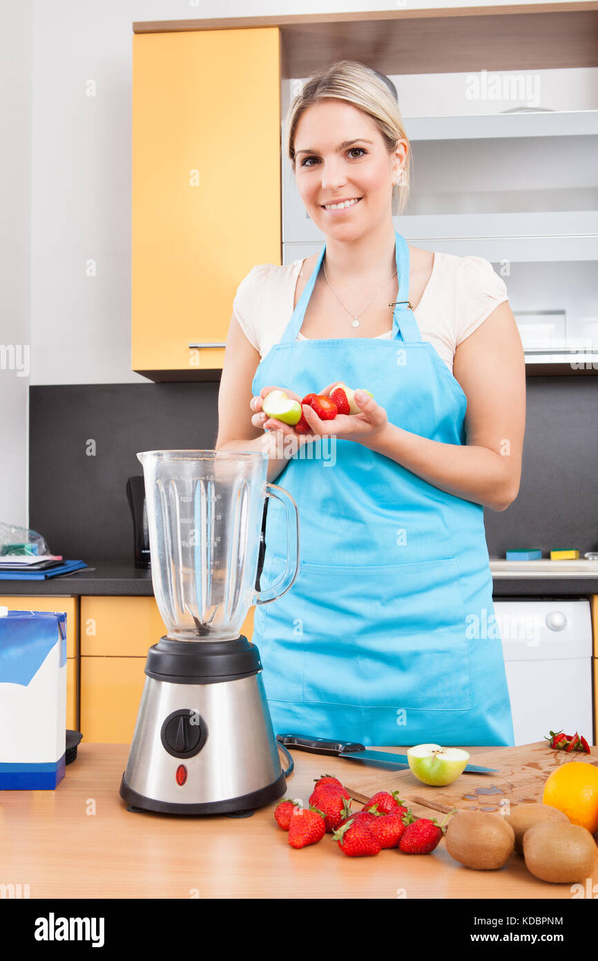 Glückliche Frau Vorbereitung Erdbeer Milchshake in der Schleifmaschine Stockfoto