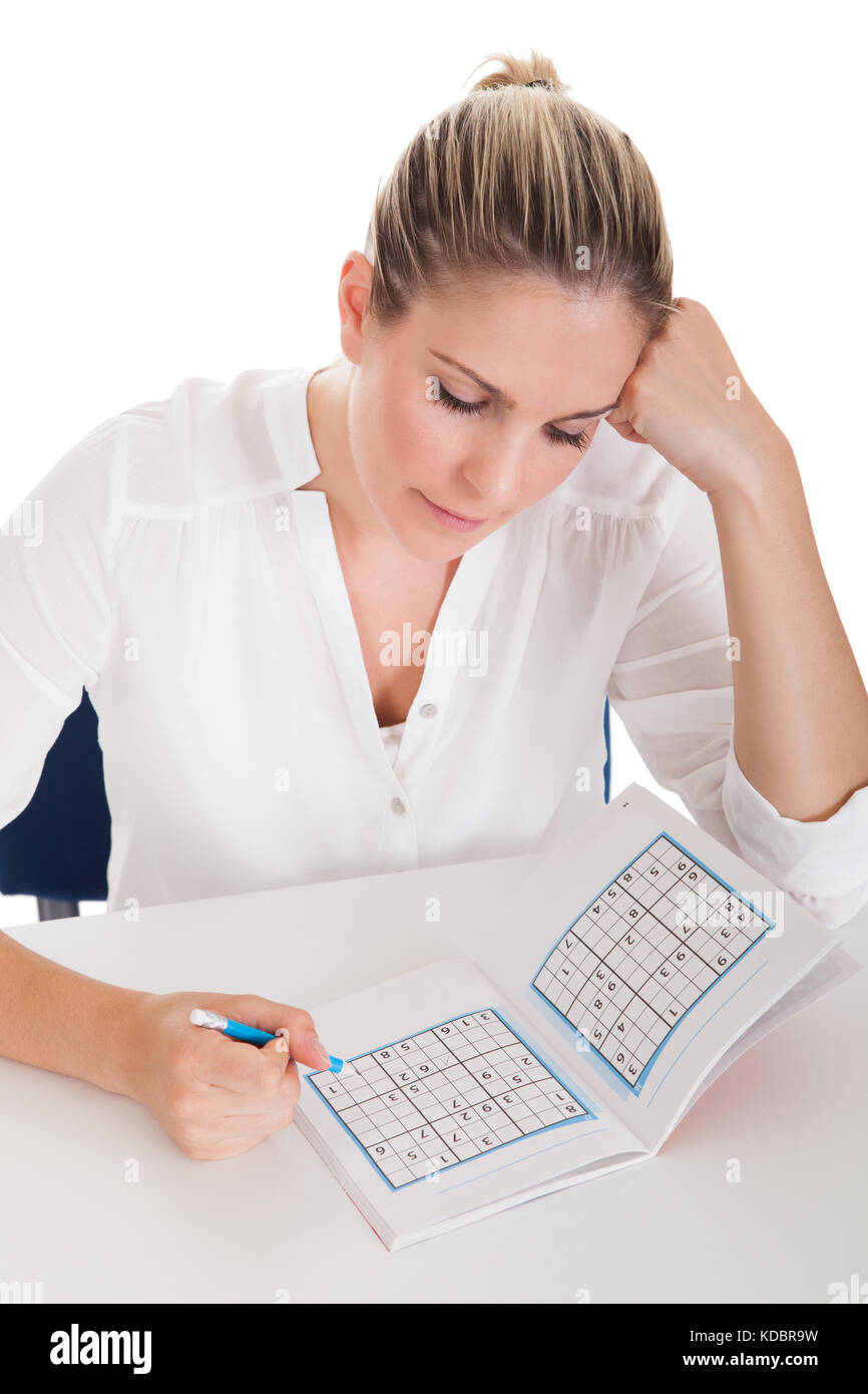 Junge Frau auf weißem Hintergrund Sudoku lösen Stockfoto