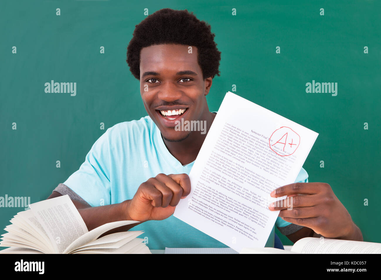Glücklich afrikanische männlichen Studenten zeigt eine Papier mit perfekten Grade ein Plus im Klassenzimmer Stockfoto