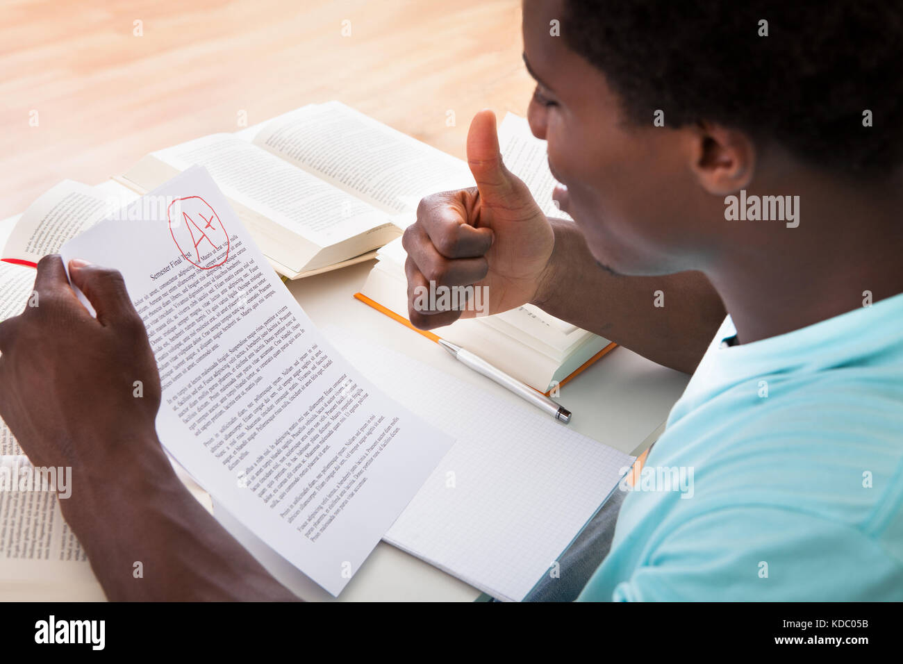 Glücklich afrikanische männlichen Studenten zeigt eine Papier mit perfekten Grade ein Plus im Klassenzimmer Stockfoto