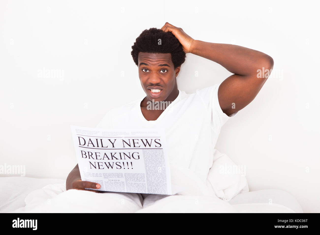 Porträt von besorgt jungen afrikanischen Mann mit Zeitung am Bett sitzen Stockfoto