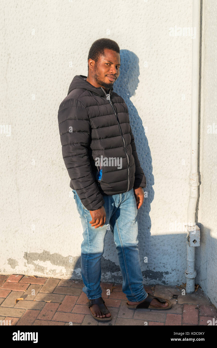 Porträt eines nigerianischen Mannes mit schwarzer Jacke an der weißen Wand, Italien. Stockfoto