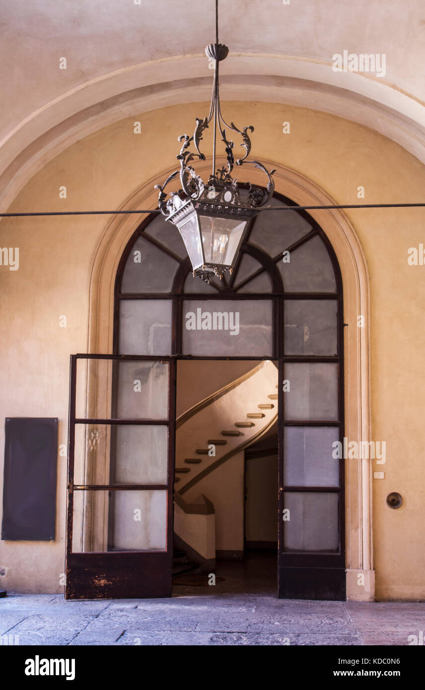 Eingang zum Italienischen Wohnungen geschwungene Treppenhaus in Sicht, Pfirsich aus hellem Stein arbeiten, große antike Laterne Leuchte über der Tür Stockfoto