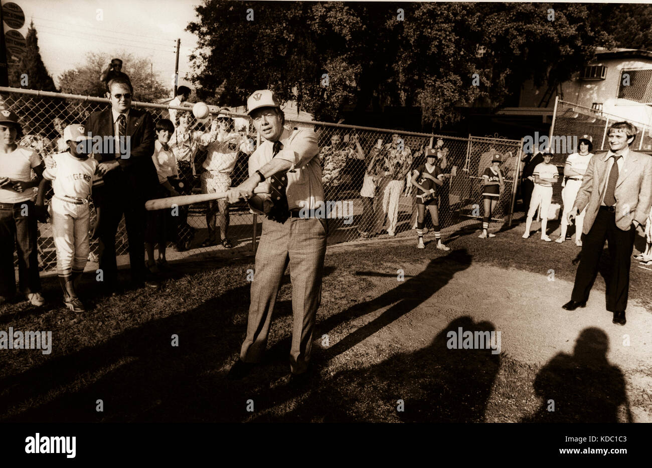Pressesprecher des Weißen Hauses Jody Powell (rechts) sieht zu, wie Präsident Carter auf einem Baseballfeld der Mittelschule eine Runde spielt. Stockfoto