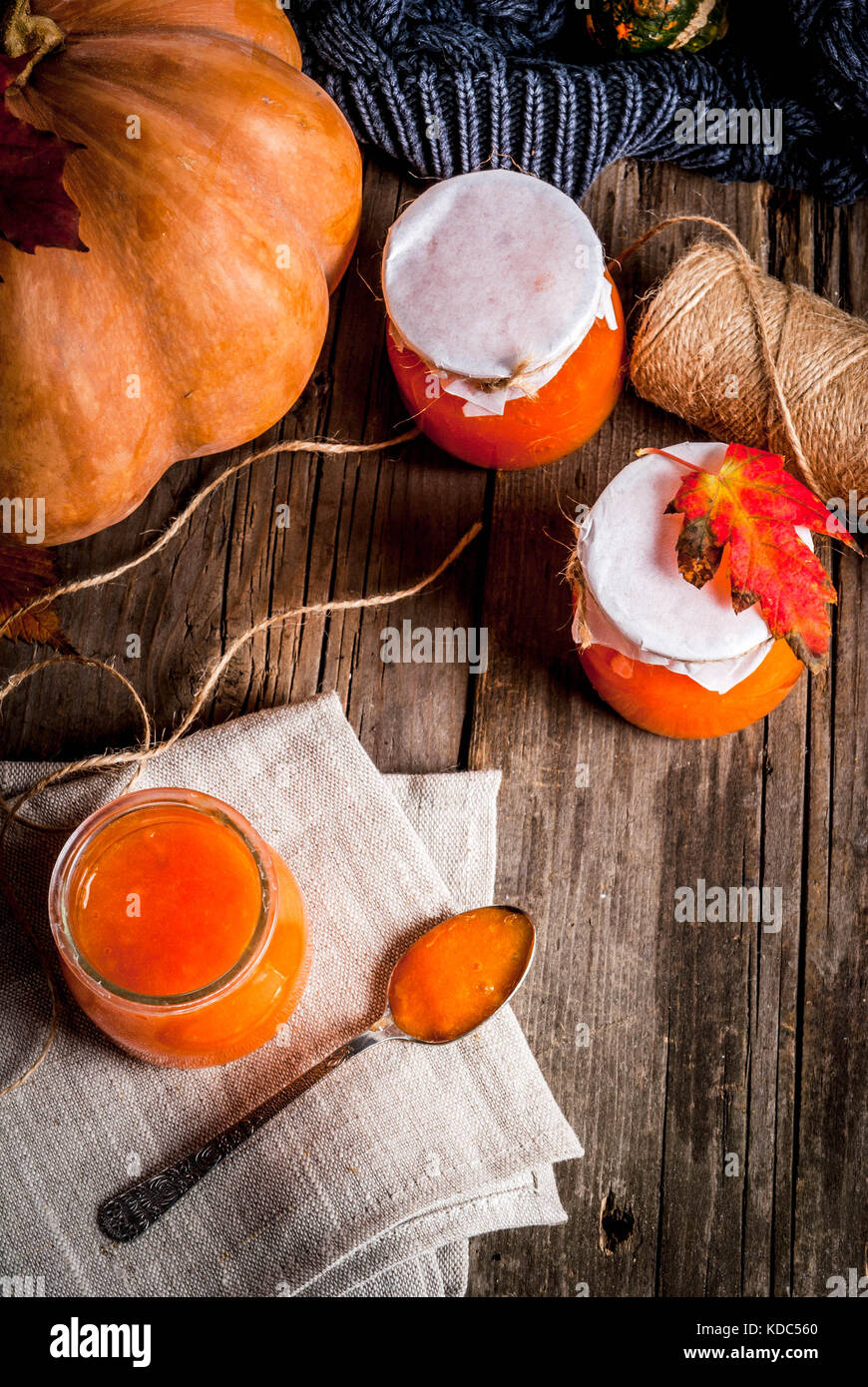 Herbst Rezepte, Gerichte aus einem Kürbis. süß würzige Kürbis Marmelade in einer Umhüllung jar, mit einem Löffel, auf einer alten rustikalen Holztisch mit Kürbissen dekoriert, Stockfoto