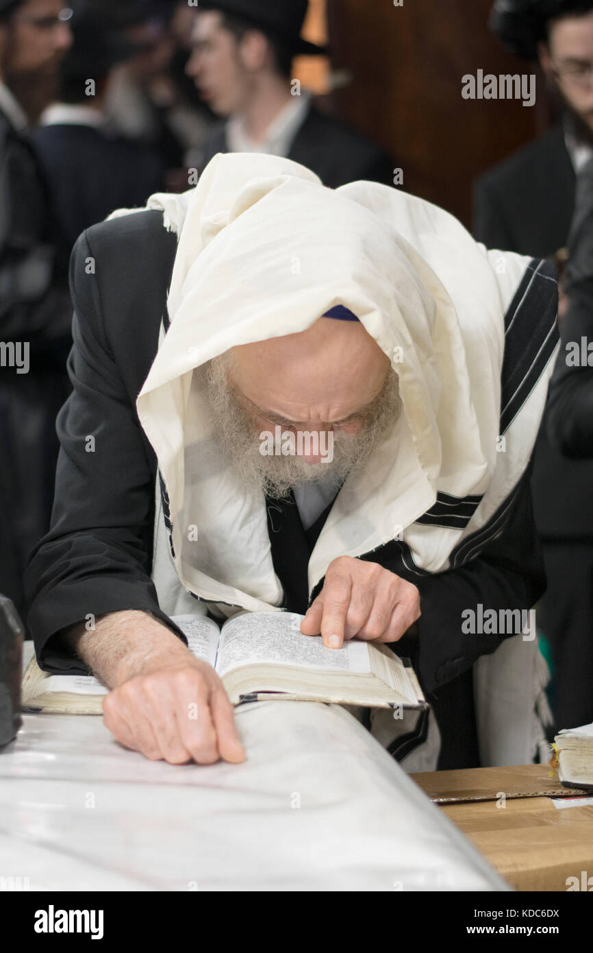 Einen religiösen Jüdischen Mann, der betet trägt einen tallit und hält seinen Platz in seinem Gebetbuch. In einer Synagoge in Brooklyn, New York. Stockfoto