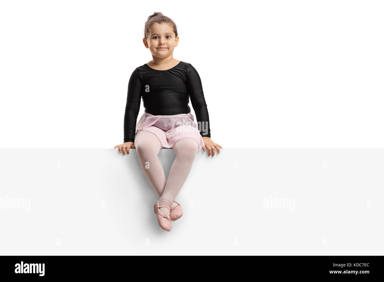 Kleine Ballerina sitzen auf einem Panel, und wenn man die Kamera auf weißem Hintergrund Stockfoto