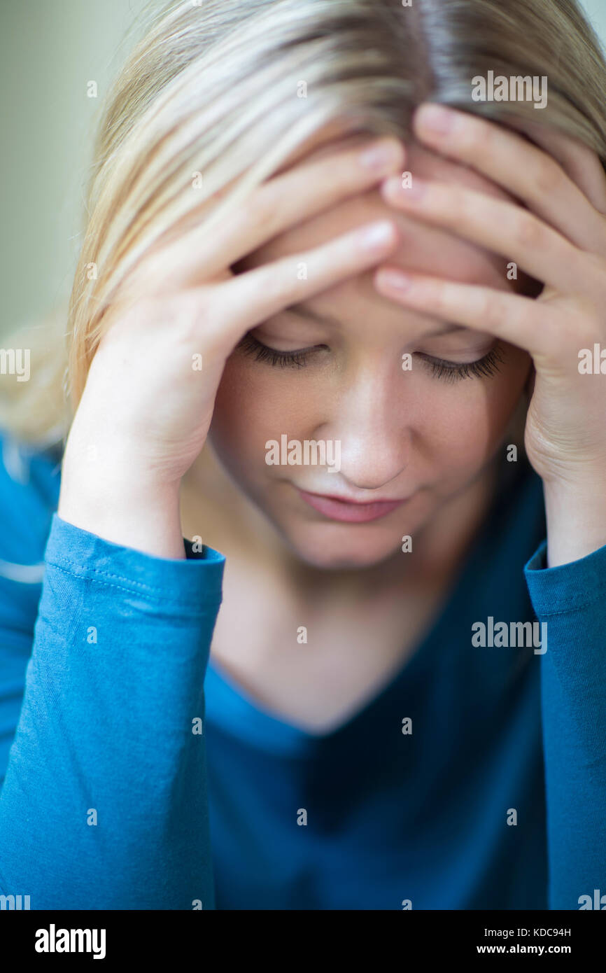Junge Frau, die unter Depressionen leiden, mit Kopf in den Händen Stockfoto