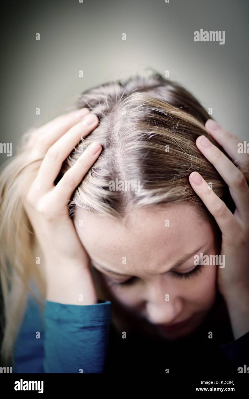 Junge Frau, die unter Depressionen leiden, mit Kopf in den Händen Stockfoto