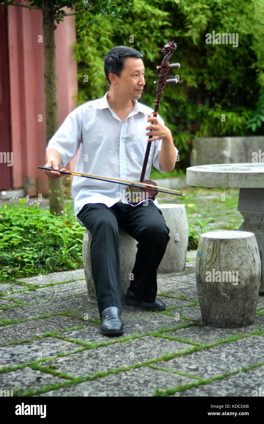 Alte chinesische Mann spielt erchu oder chinesische Geige im Garten am Abend Stockfoto