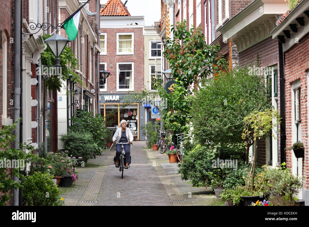 Eine Frau mit dem Fahrrad entlang eines verkehrsfreien Seitenstraße in Haarlem Stadtzentrum, Nord Holland, Niederlande. Stockfoto