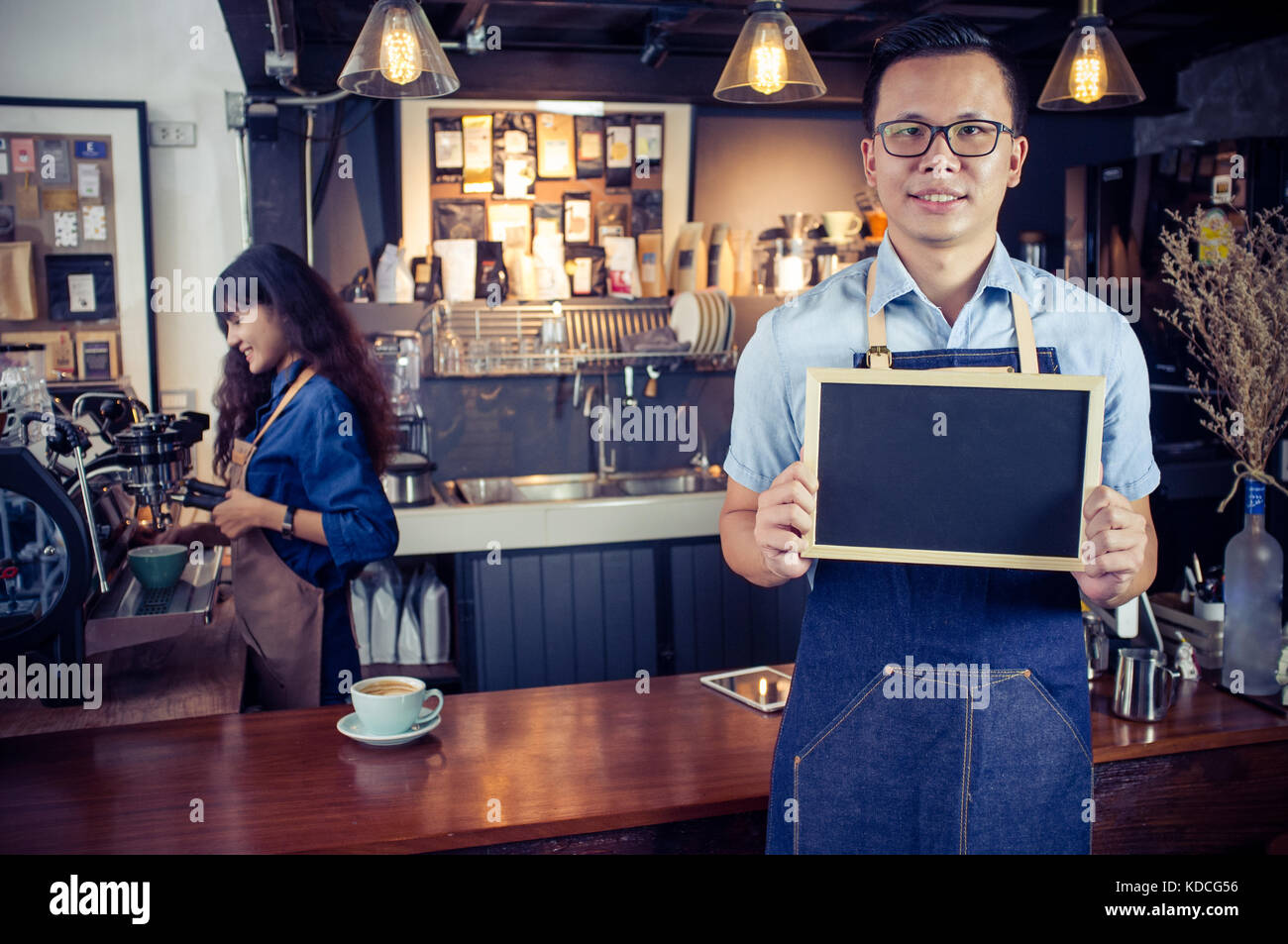 Portrait von lächelnden asiatischer barista Holding leere Schiefertafel Menü im Coffee Shop. Cafe Restaurant Service, Inhaber kleiner Unternehmen, die Lebensmittel- und Getränkeindustrie Stockfoto