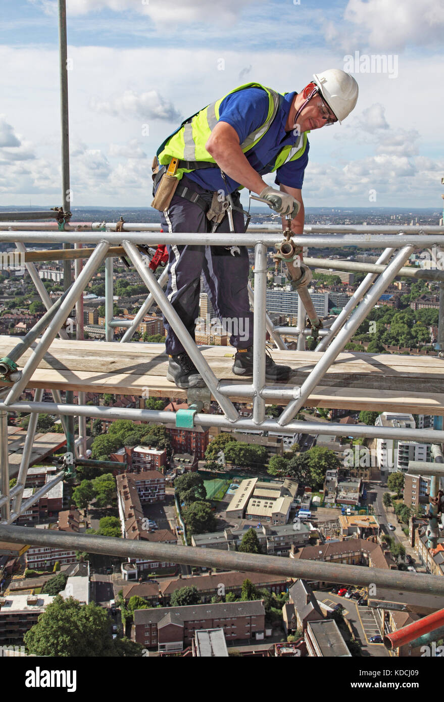 Ein gerüstbauer errichtet eine temporäre Arbeit Plattform hoch über London im Zuge der Sanierung der Kerle Krankenhaus Turm. Zeigt Bermondsey & Southwark darüber hinaus. Stockfoto