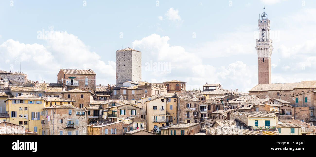 Horizontale Foto mit Blick auf den Rathausturm über die Häuser und Gebäude in der historischen Altstadt von Siena in Italien Toskana. der Himmel ist blau Stockfoto