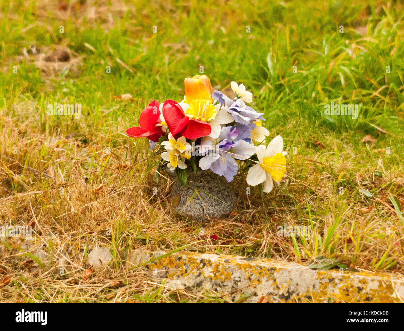 Bündel von gefälschten Plastikblumen auf Gras Grab, Essex, England, Großbritannien Stockfoto