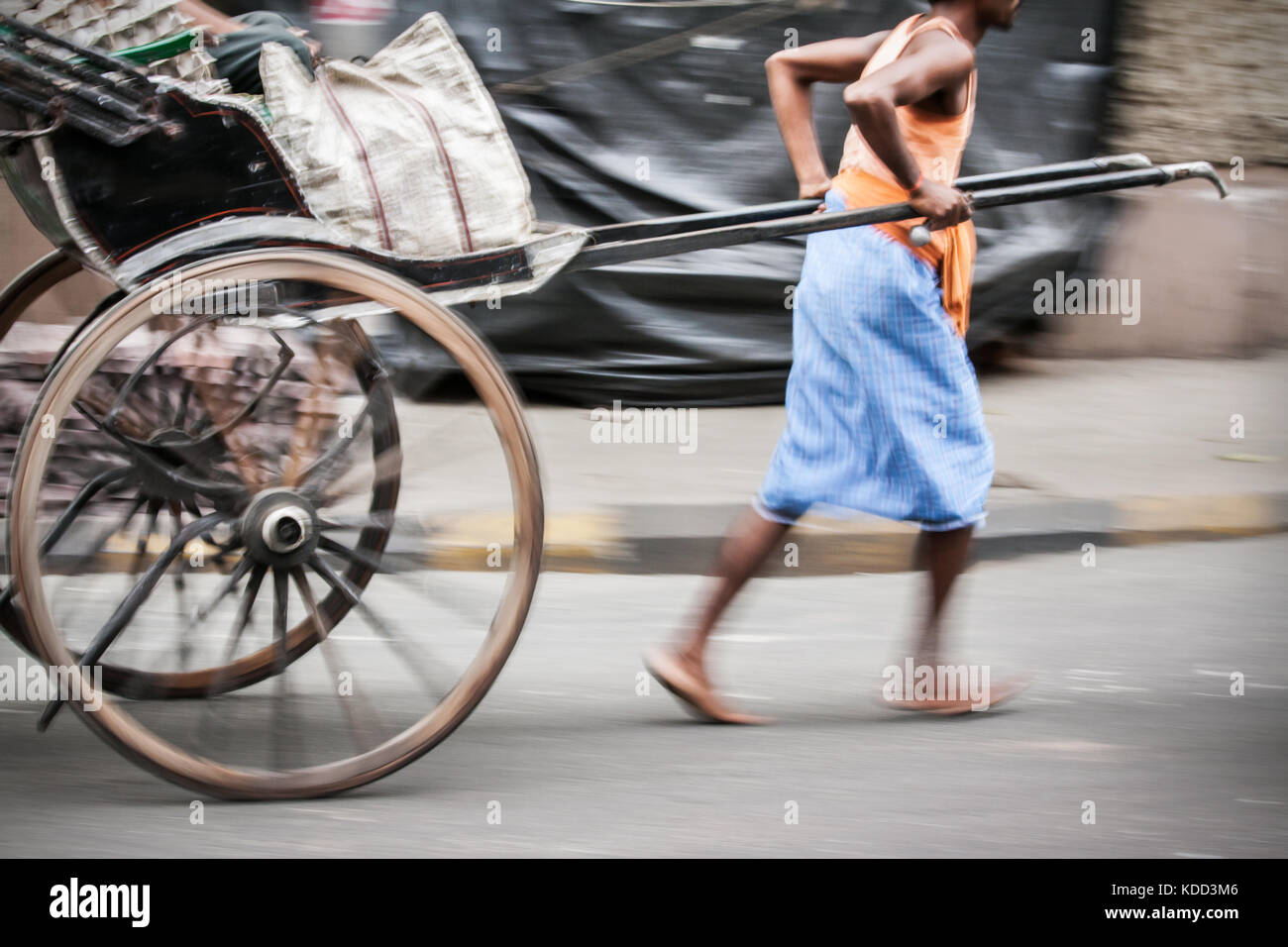 Indische Mann in der Bewegung Ziehen einer Hand gezeichnet Rikscha auf Kolkata Straßen in Indien. eine der letzten Bastionen der alten Verkehrsträger Stockfoto