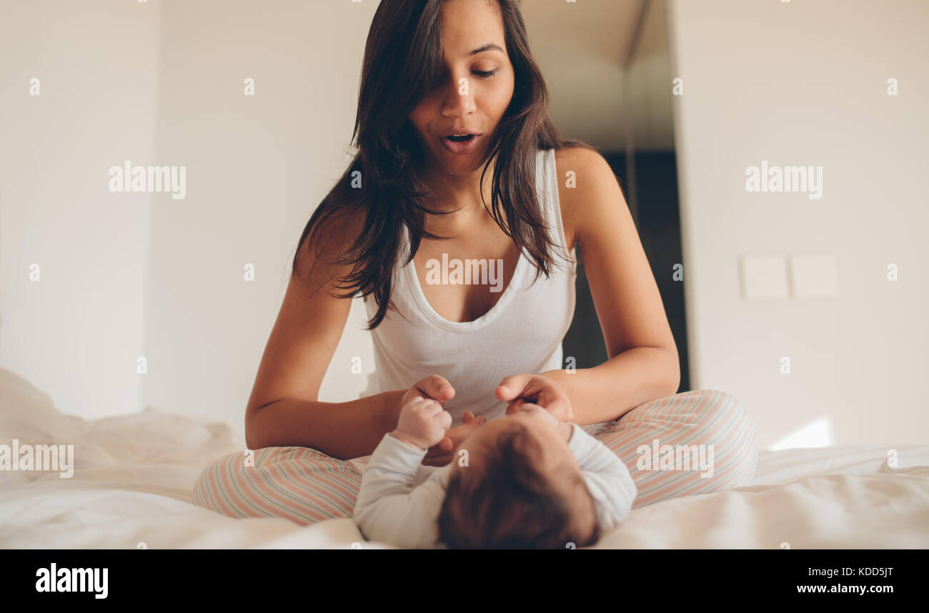 Frau sitzt auf dem Bett und spielt mit ihrem Baby zu Hause. Mutter und Sohn spielen im Schlafzimmer. Stockfoto