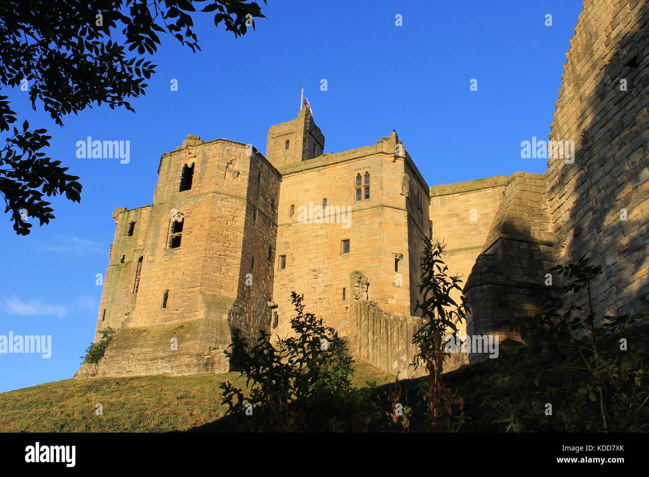 Betrachten oben Warkworth Castle auf seiner Stange hoch über dem Fluß Coquet im hellen Sonnenschein, abends Warkworth, Northumberland, Großbritannien Stockfoto