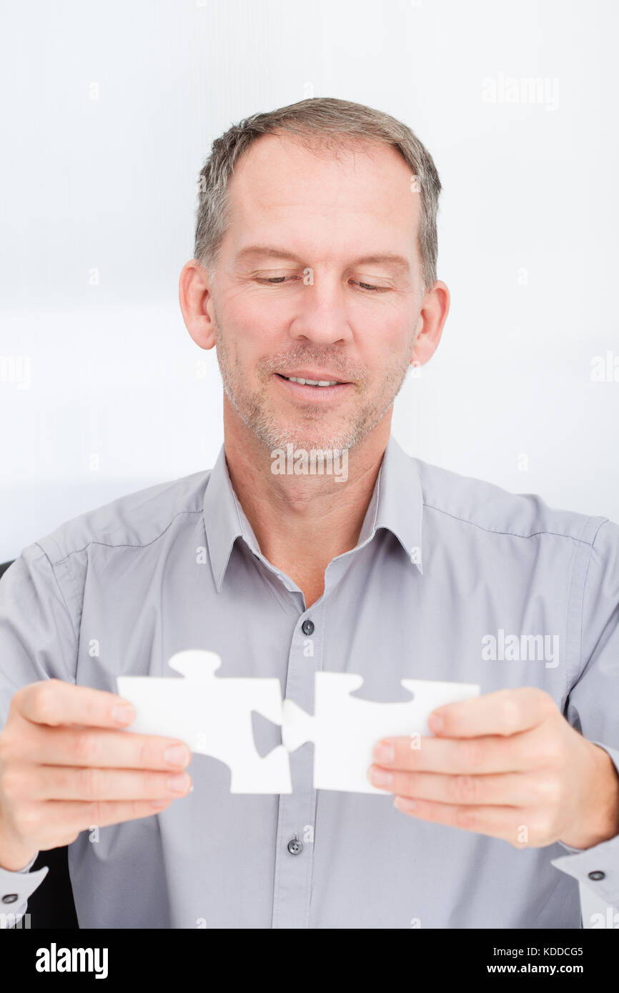 Porträt eines reifen Geschäftsmann Lösung Puzzle im Büro Stockfoto