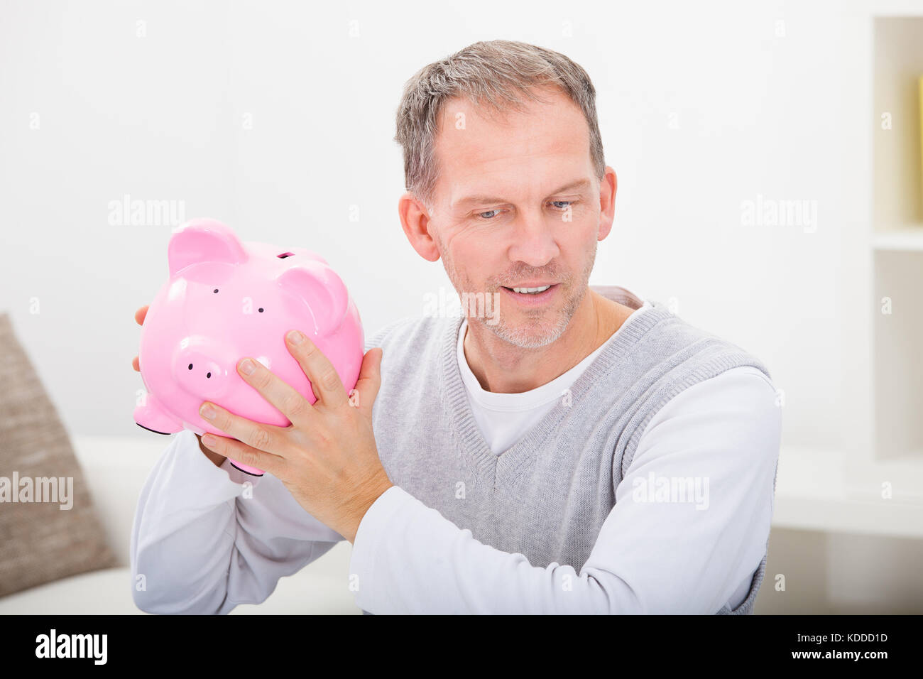 Porträt eines reifen Mannes hält Sparschwein Stockfoto