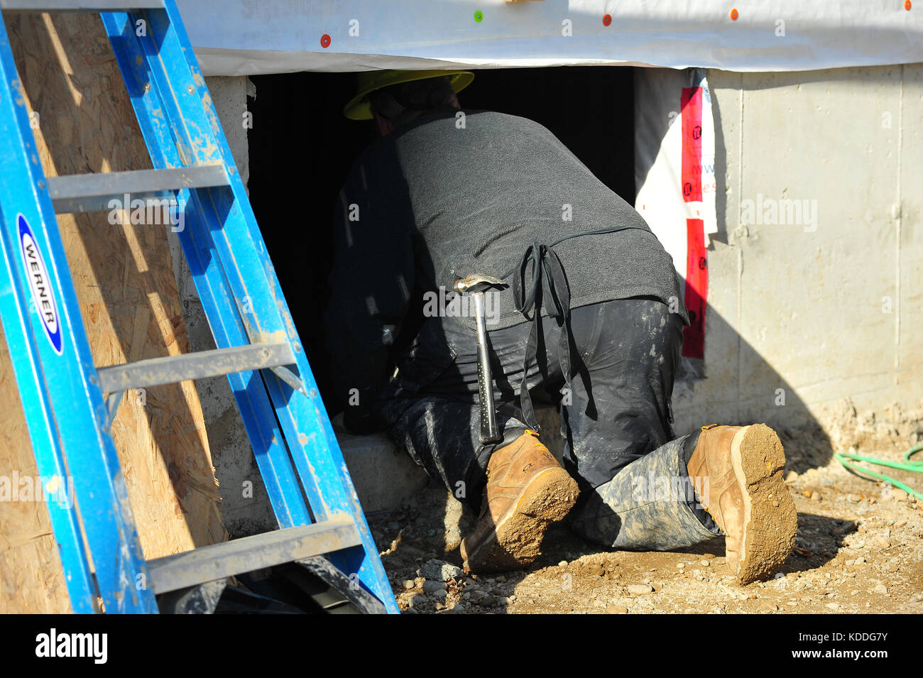 Ein Bauherr lehnte sich durch ein Kellerfenster auf einer Baustelle in Kanada. Stockfoto