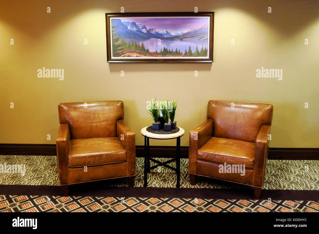 Zwei braunen Ledersesseln, einem Beistelltisch und einem Bild für eine Lobby. Stockfoto